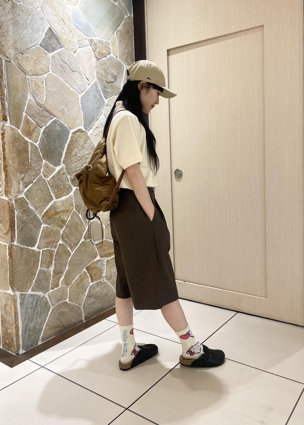 ブラウン系のバックパック/リュック、ブラウン系のその他パンツ、ベージュ系のポロシャツを着用したレディースの春コーディネートの4枚目の写真