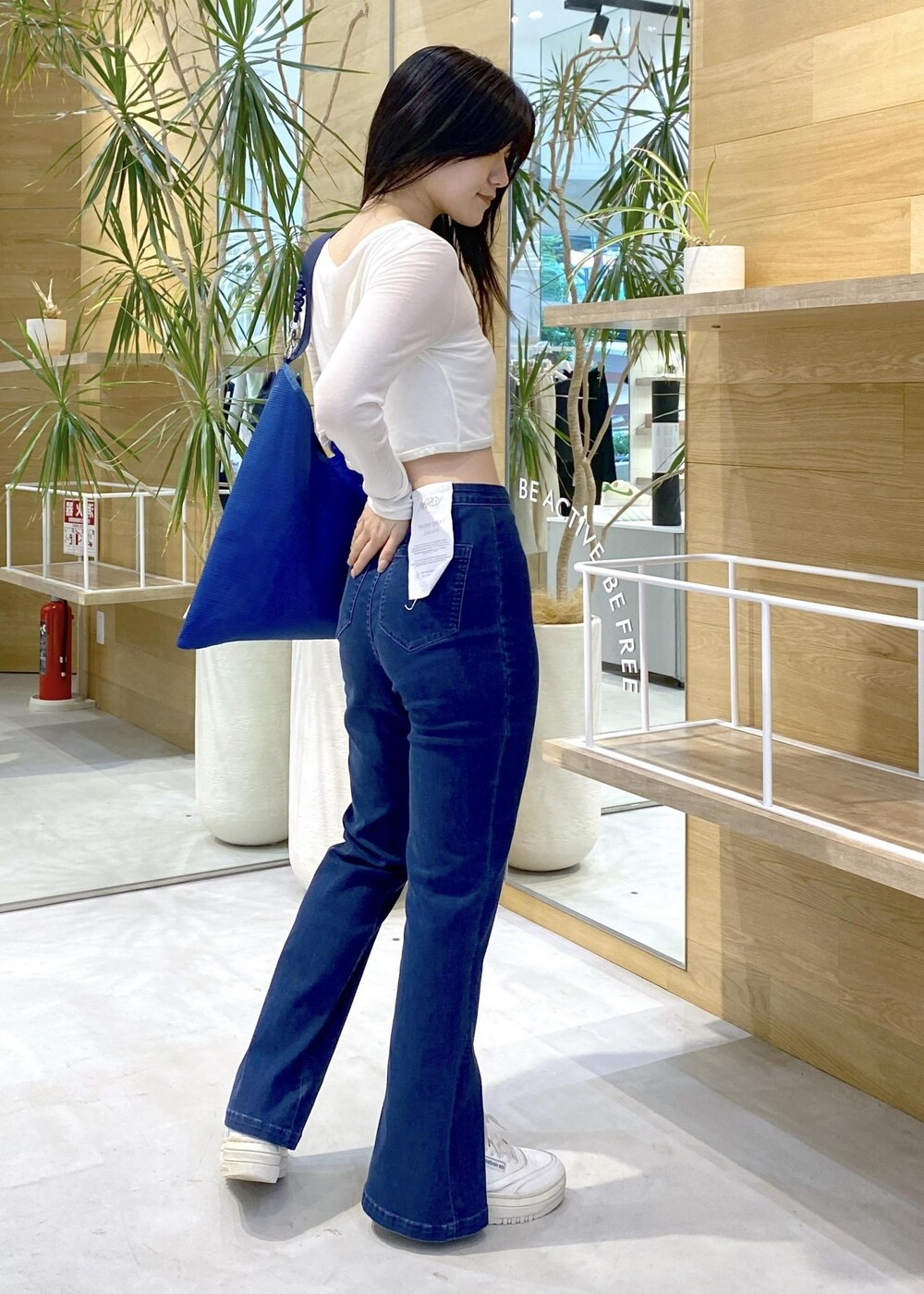 ホワイト系のスニーカー、ブルー系のデニムパンツ、ブルー系のトートバッグを着用したレディースの秋コーディネートの4枚目の写真