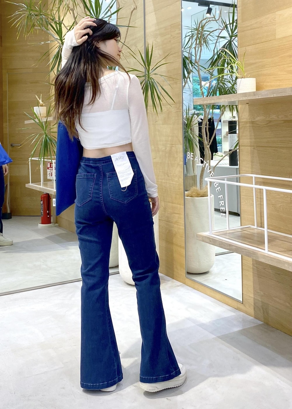 ホワイト系のスニーカー、ブルー系のデニムパンツ、ブルー系のトートバッグを着用したレディースの秋コーディネートの6枚目の写真