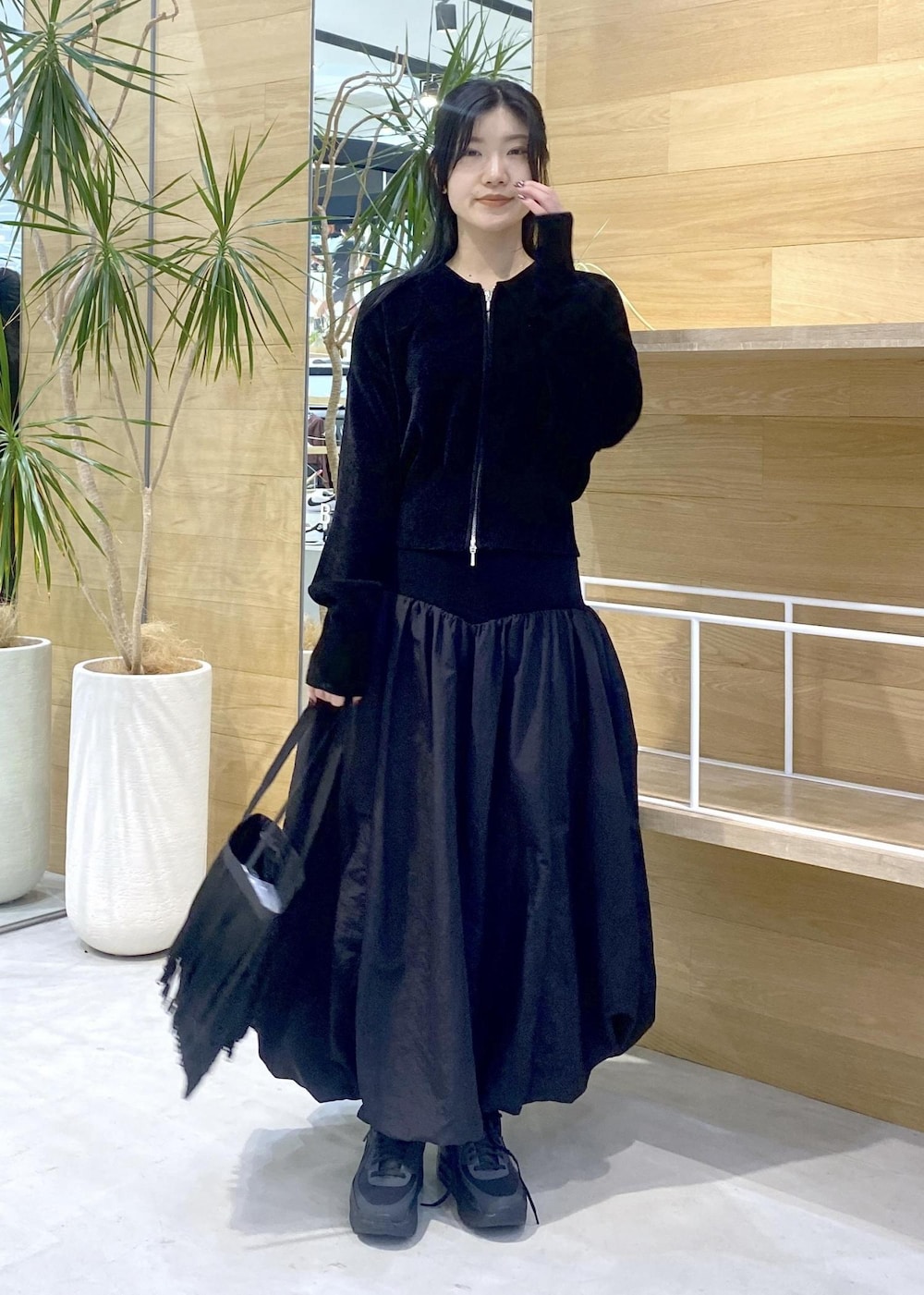 ブラック系のスカート、ブラック系のカーディガン/ボレロ、ブラック系のスニーカーを着用したレディースの冬コーディネートの2枚目の写真