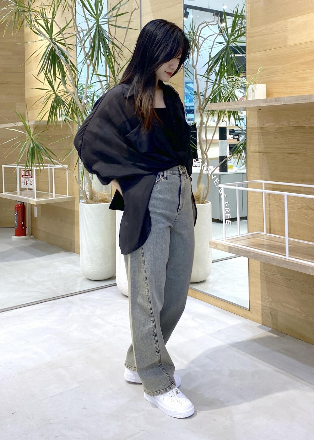 ホワイト系のスニーカー、ブラック系のキャミソール、ベージュ系のデニムパンツを着用したレディースの秋コーディネートの3枚目の写真