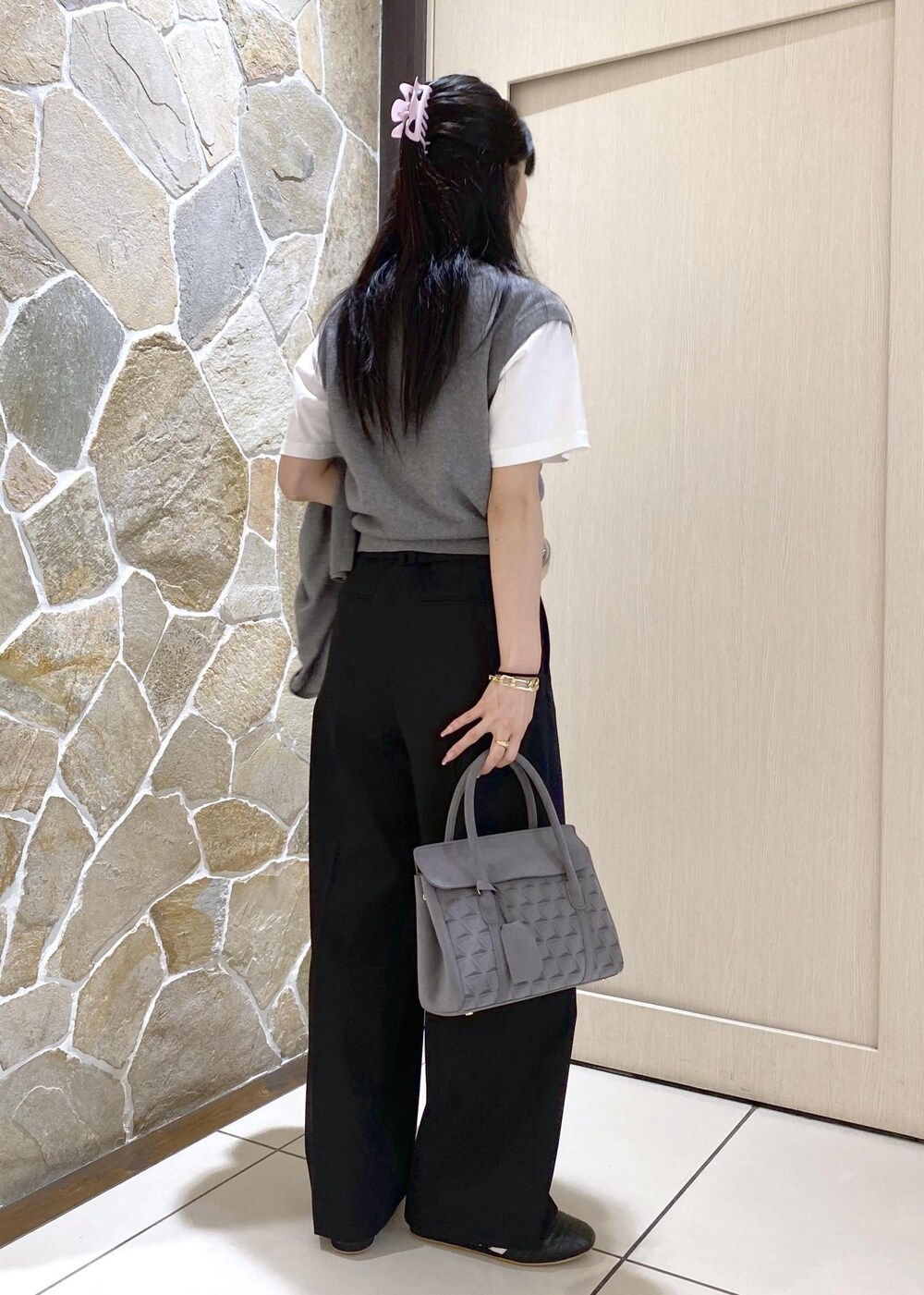 ブラック系のスニーカー、グレー系のニット/セーター、ブラック系のスラックスを着用したレディースの秋コーディネートの4枚目の写真