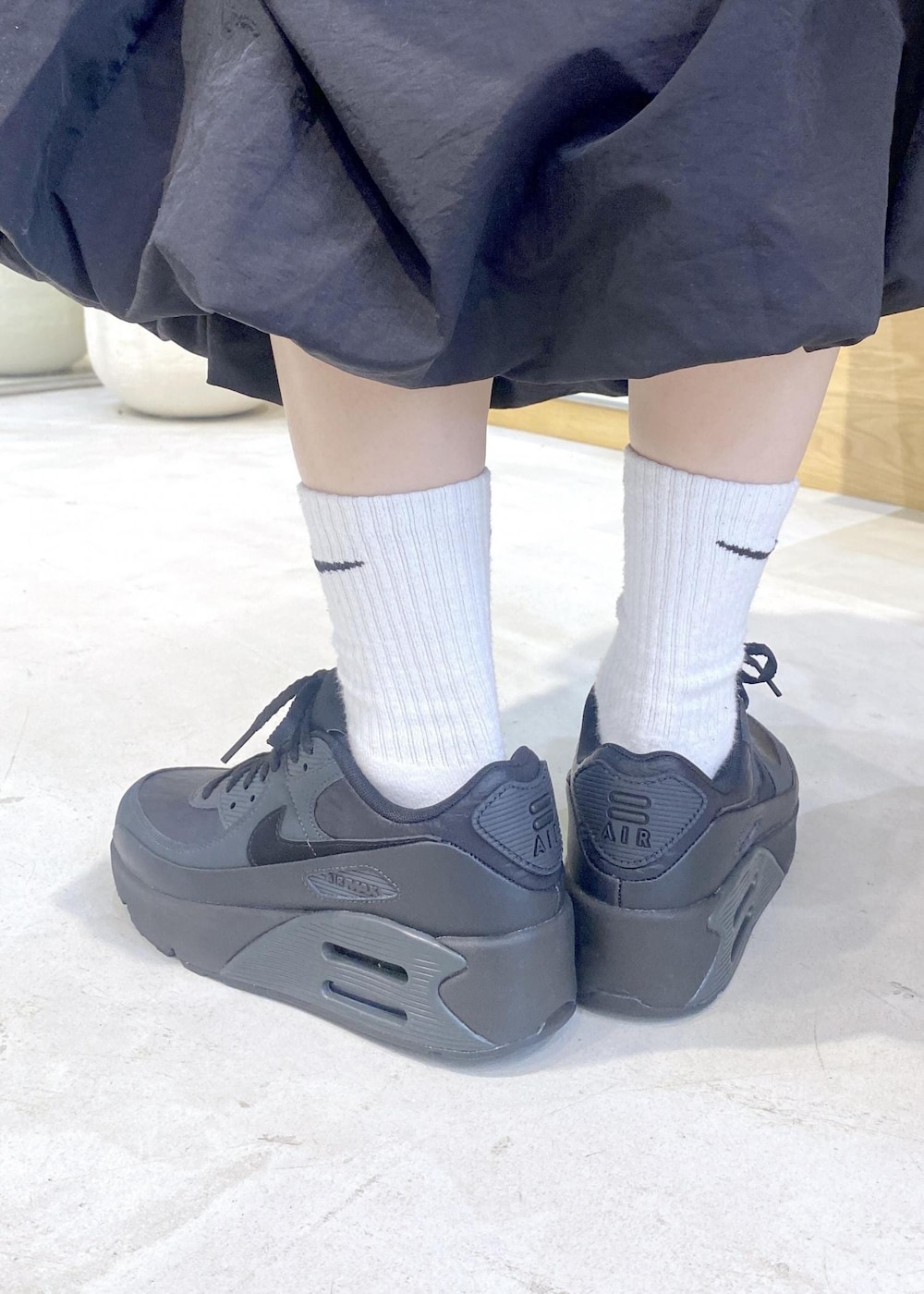 ブラック系のスカート、ブラック系のカーディガン/ボレロ、ブラック系のスニーカーを着用したレディースの冬コーディネートの9枚目の写真