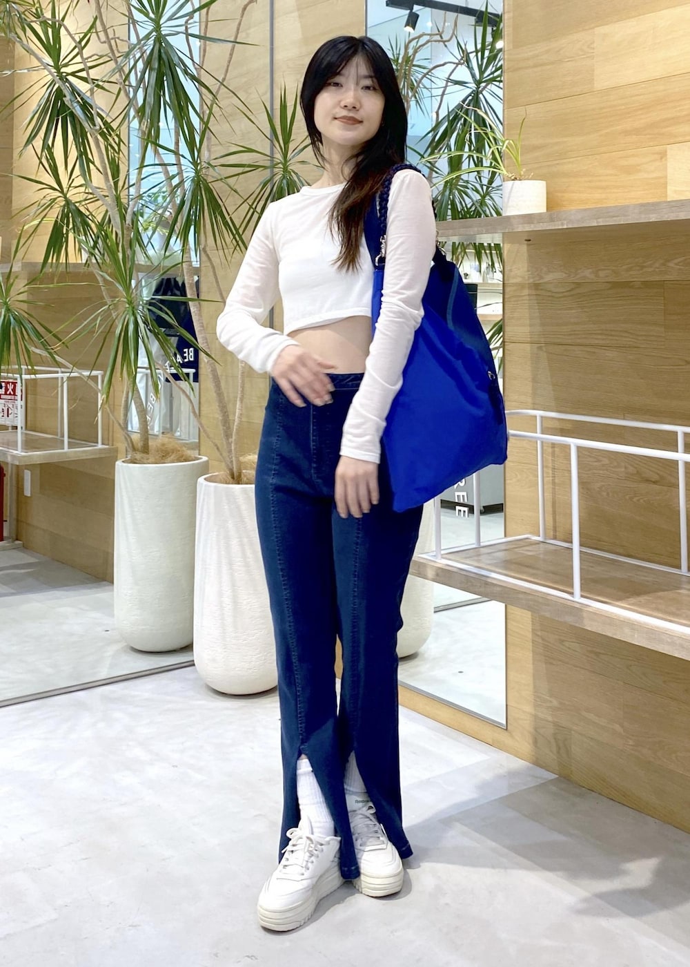 ホワイト系のスニーカー、ブルー系のデニムパンツ、ブルー系のトートバッグを着用したレディースの秋コーディネートの2枚目の写真