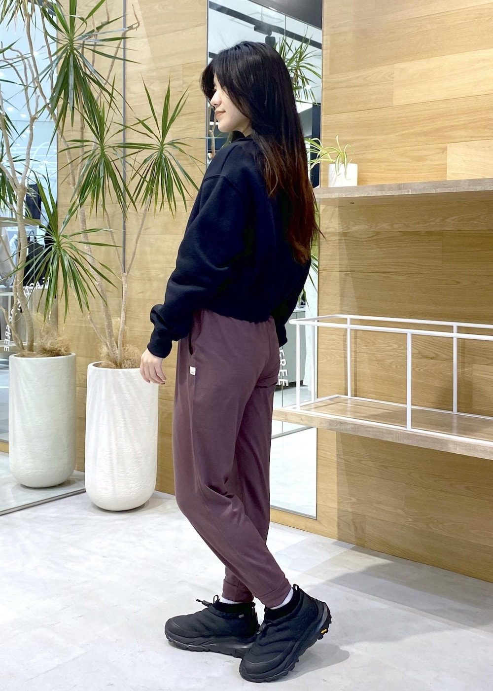 ピンク系のスラックス、ブラック系のスニーカー、ブラック系のスウェットを着用したレディースの秋コーディネートの6枚目の写真