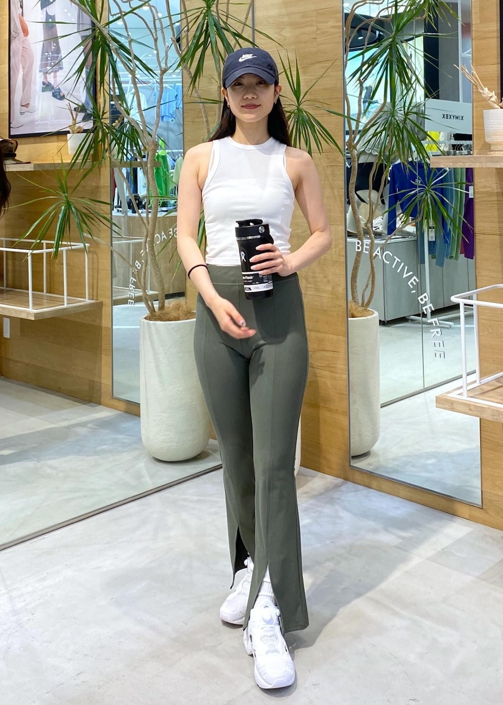 ホワイト系のスニーカー、ホワイト系のタンクトップ、ブラック系のキャップを着用したレディースの夏コーディネートの2枚目の写真