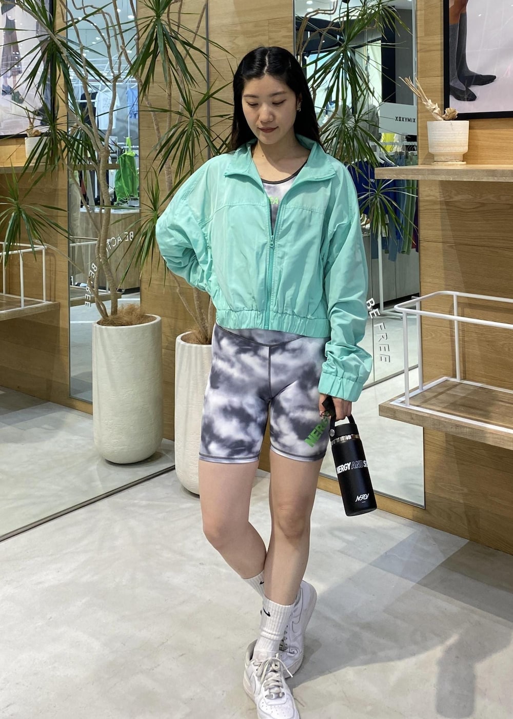 ホワイト系のスニーカー、グリーン系のナイロンジャケット、ブラック系のブラジャーを着用したレディースの春コーディネートの3枚目の写真