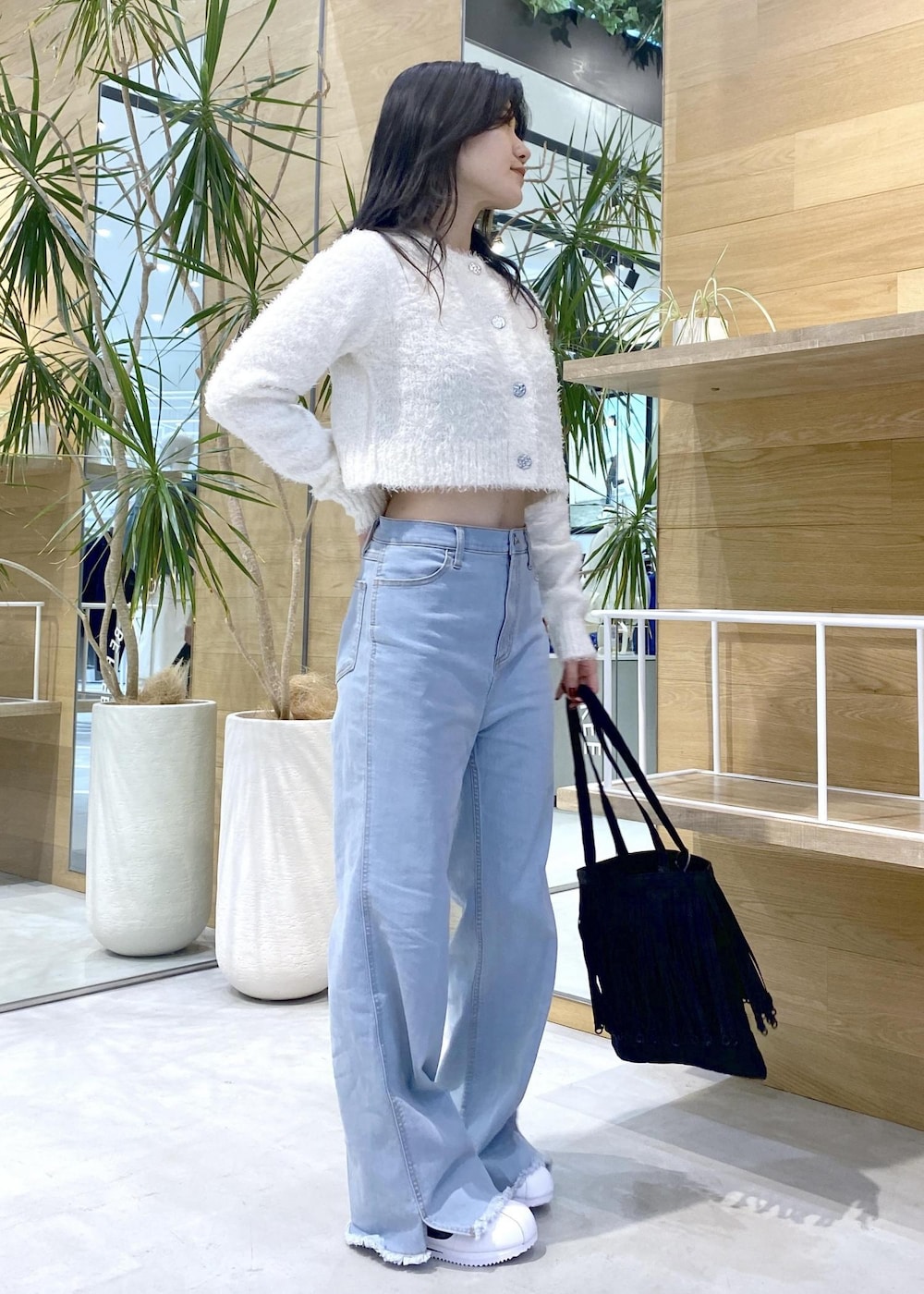 ホワイト系のスニーカー、ブルー系のデニムパンツ、ブラック系のトートバッグを着用したレディースの秋コーディネートの7枚目の写真