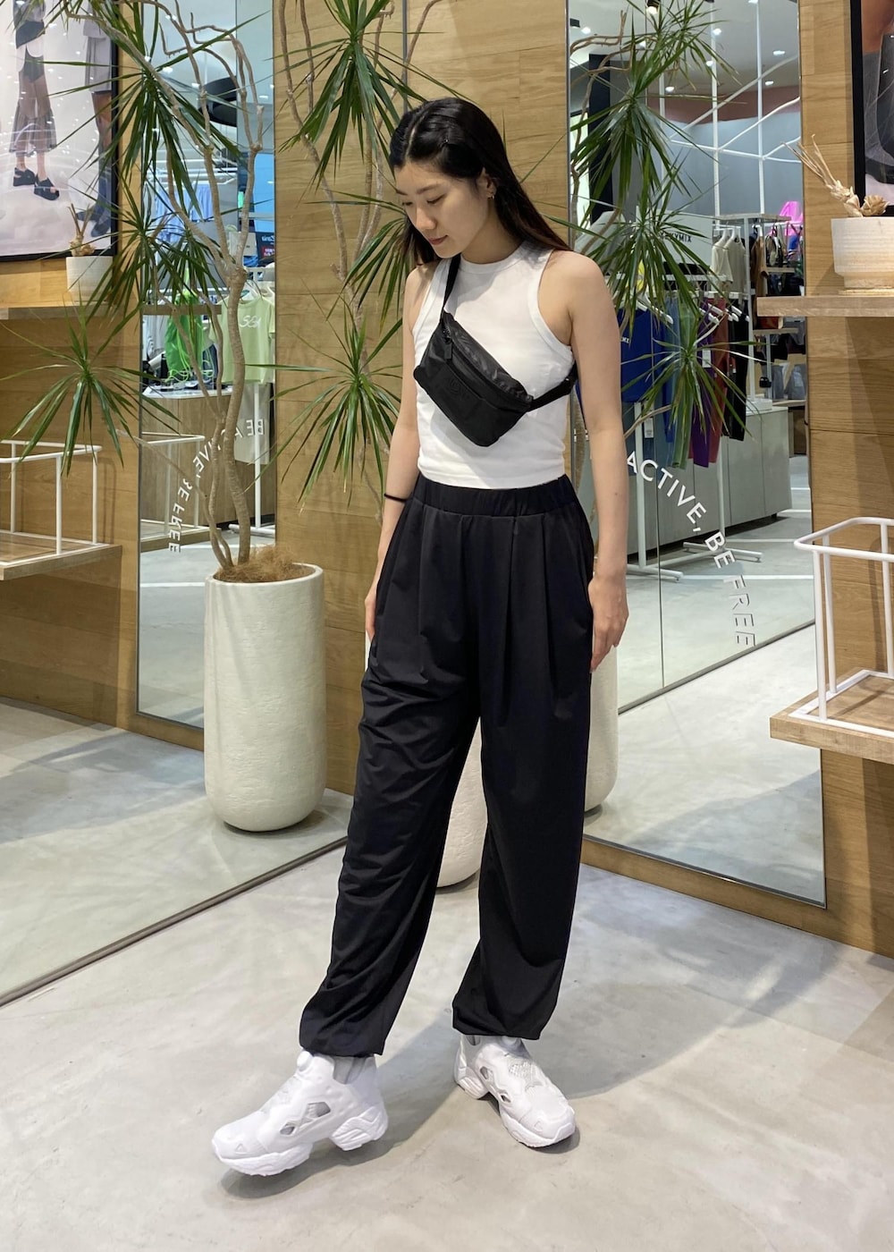 ブラック系のカーゴパンツ、ホワイト系のスニーカー、ホワイト系のタンクトップを着用したレディースの春コーディネートの2枚目の写真
