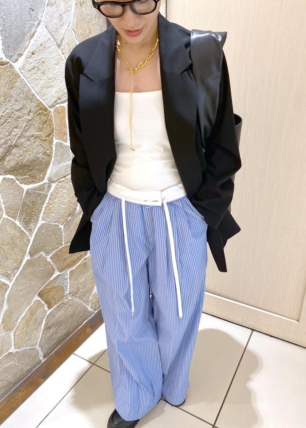 ブルー系のスラックス、ブラック系のテーラードジャケット、ブラック系のローファーを着用したレディースの秋コーディネートの6枚目の写真