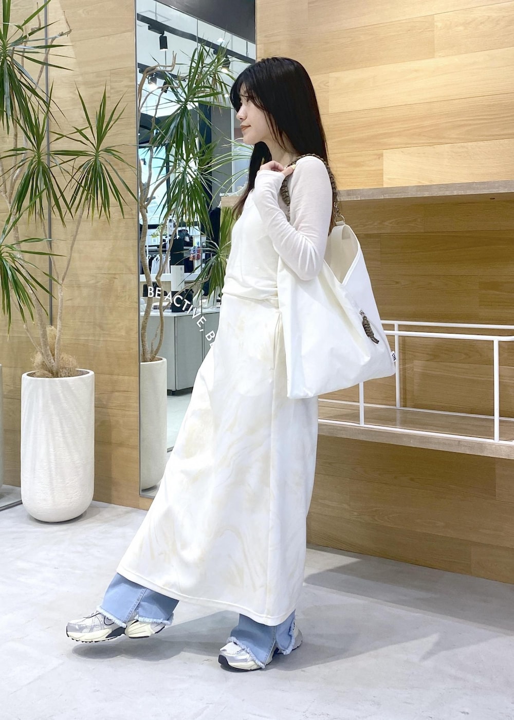 イエロー系のスカート、ホワイト系のアンサンブル、ブルー系のデニムパンツを着用したレディースの秋コーディネートの2枚目の写真