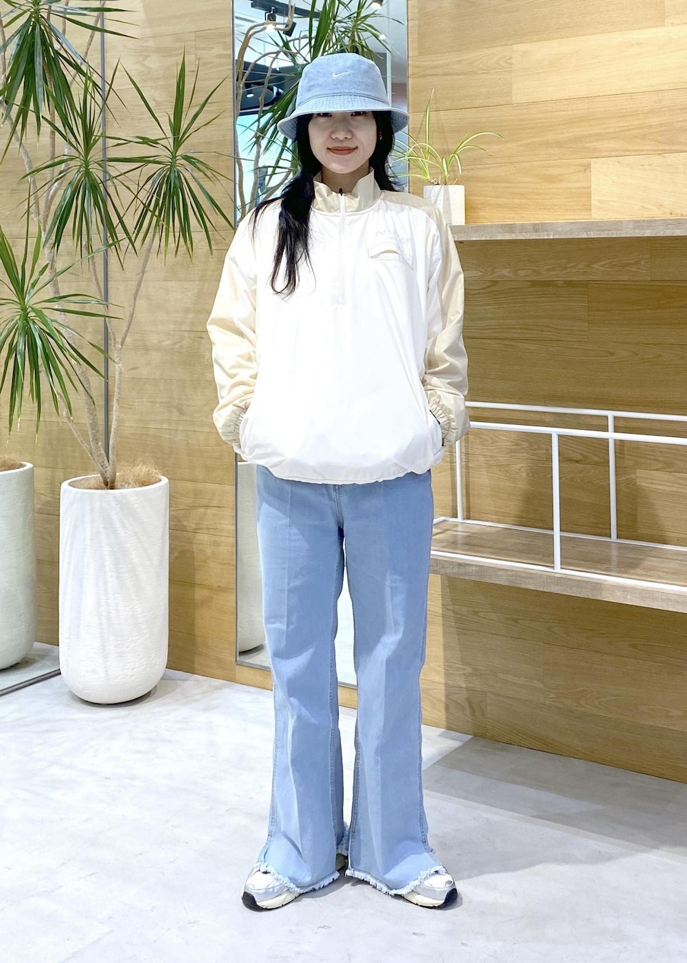 ホワイト系のスニーカー、ブルー系のデニムパンツ、ブルー系のハットを着用したレディースの秋コーディネートの2枚目の写真