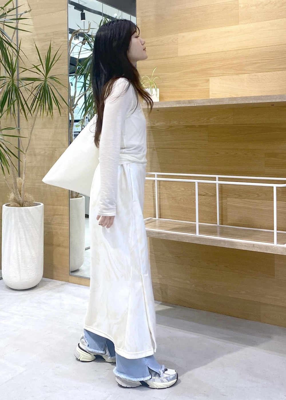 イエロー系のスカート、ホワイト系のアンサンブル、ブルー系のデニムパンツを着用したレディースの秋コーディネートの5枚目の写真