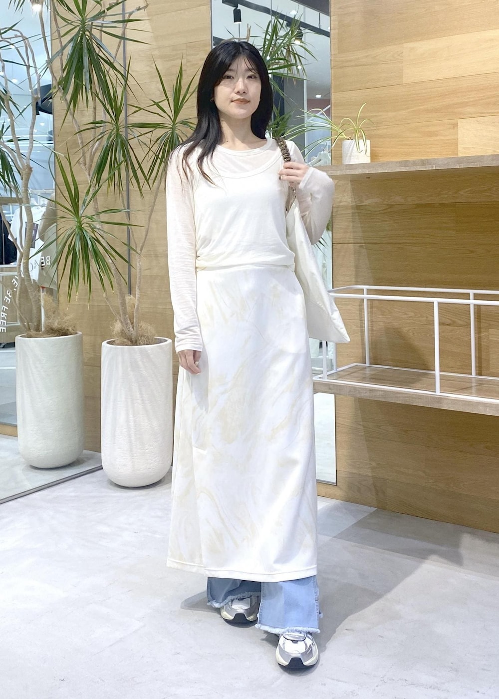 イエロー系のスカート、ホワイト系のアンサンブル、ブルー系のデニムパンツを着用したレディースの秋コーディネートの7枚目の写真