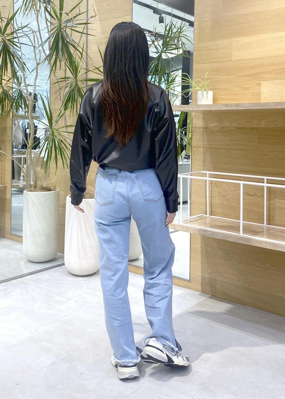 ブラック系のその他トップス、ブルー系のデニムパンツ、ホワイト系のスニーカーを着用したレディースの秋コーディネートの4枚目の写真