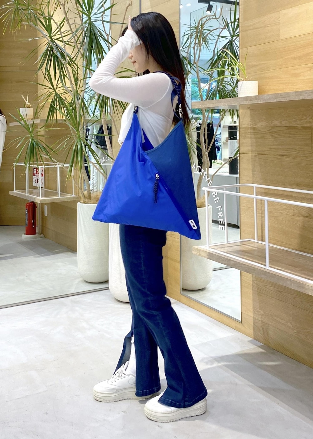 ホワイト系のスニーカー、ブルー系のデニムパンツ、ブルー系のトートバッグを着用したレディースの秋コーディネートの8枚目の写真