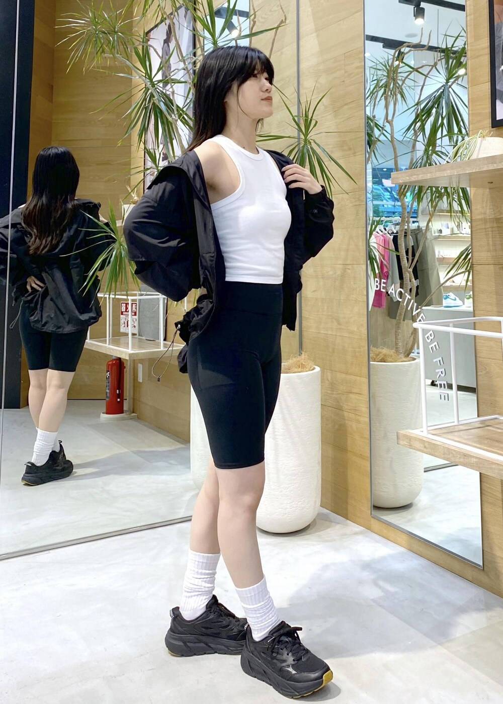 ブラック系のブルゾン、ホワイト系のタンクトップ、ブラック系のスニーカーを着用したレディースの夏コーディネートの4枚目の写真
