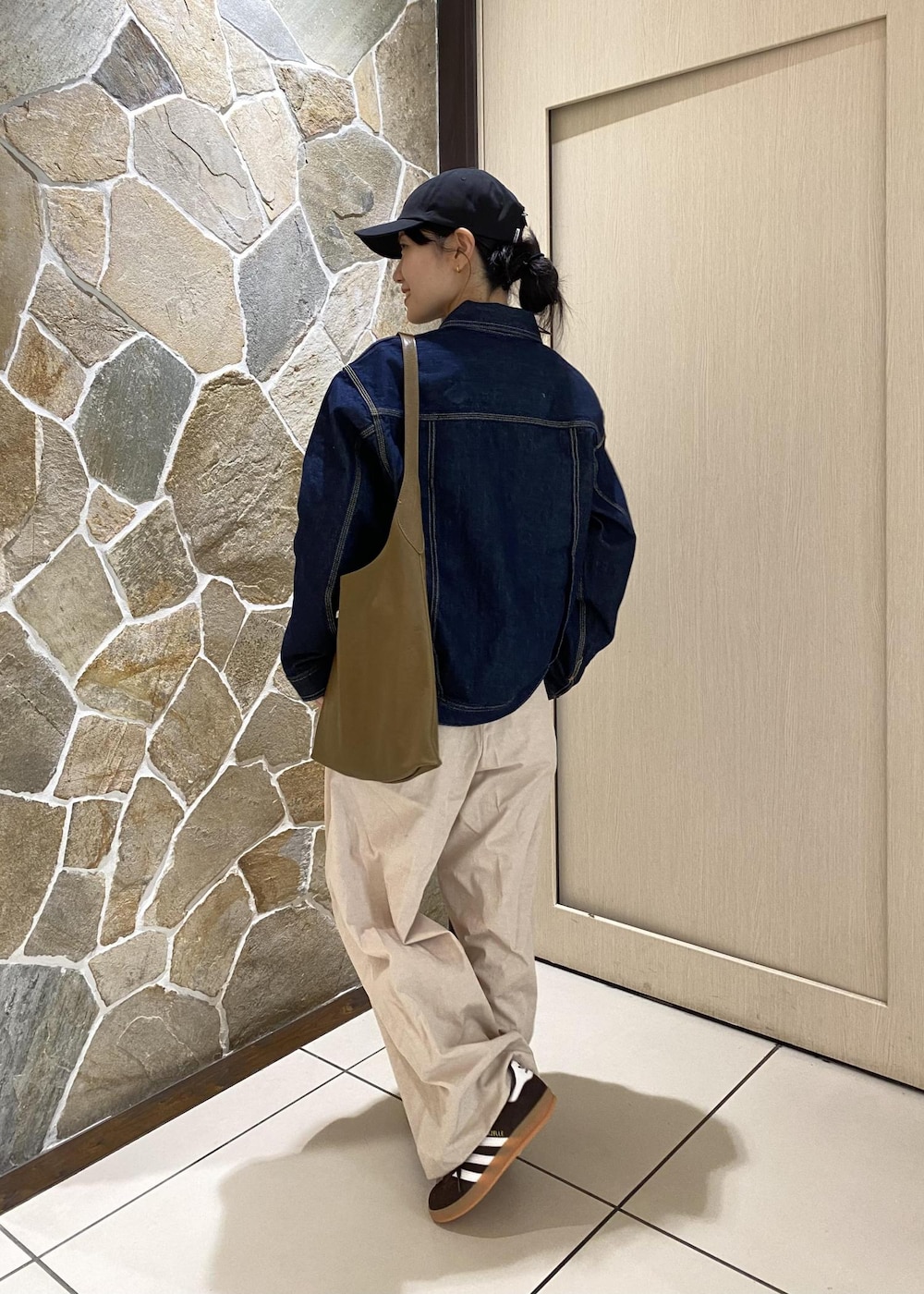 グリーン系のショルダーバッグ、ブルー系のデニムジャケット、ホワイト系のその他パンツを着用したレディースの冬コーディネートの3枚目の写真