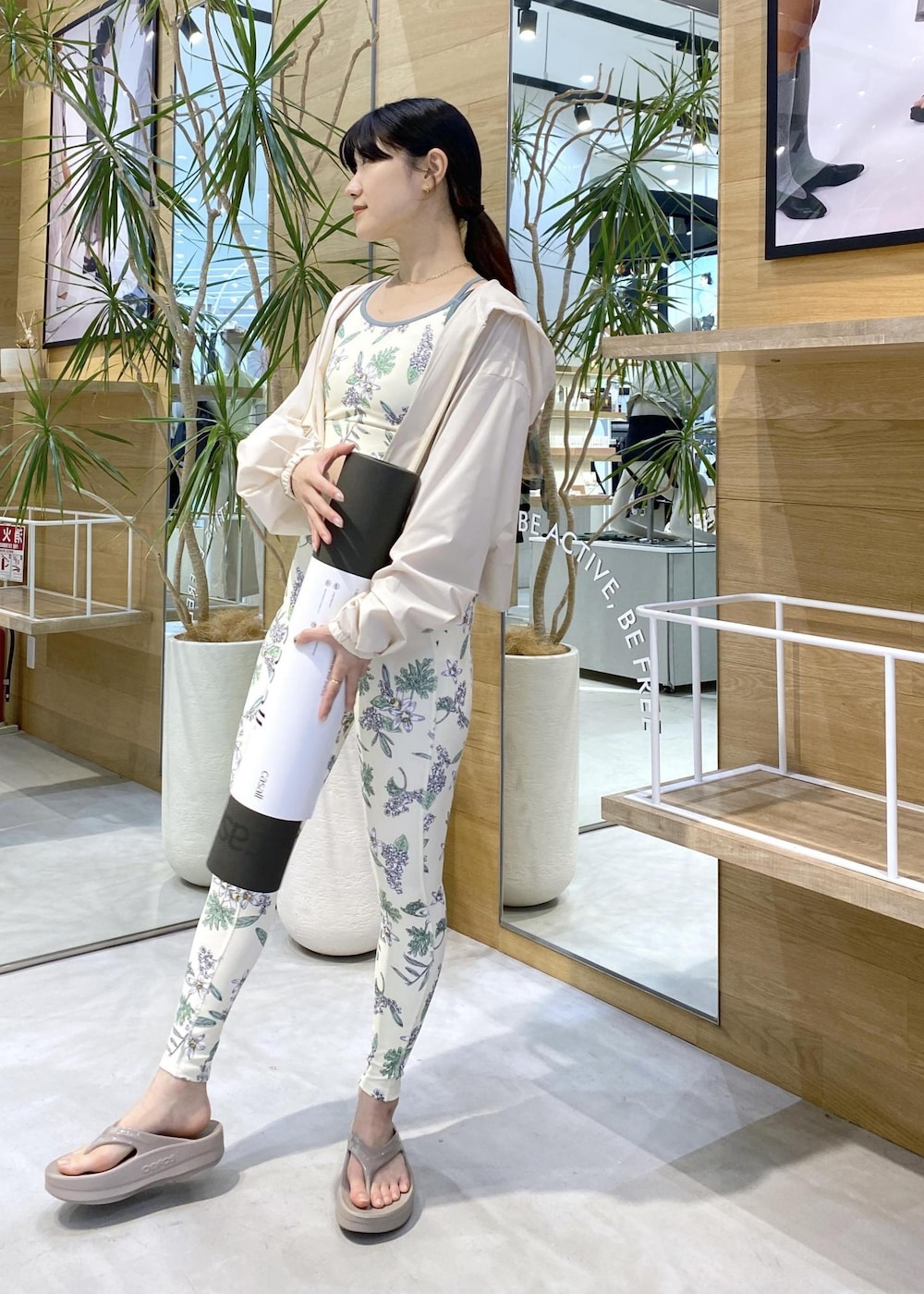 ベージュ系のサンダル、ホワイト系のラッシュガード、グリーン系のスポーツグッズを着用したレディースの夏コーディネートの2枚目の写真