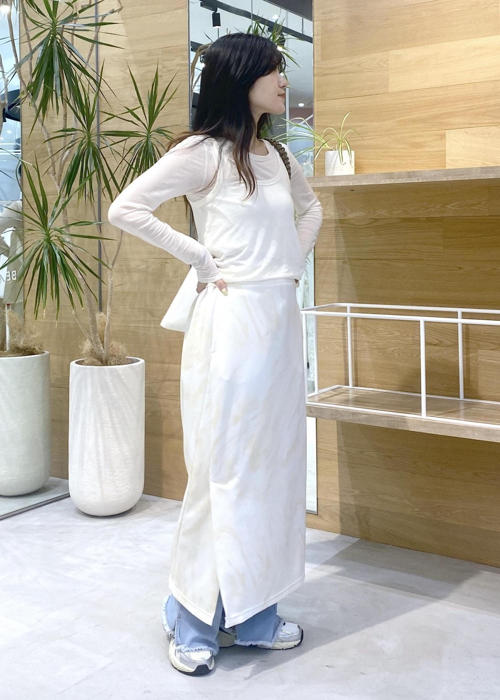 イエロー系のスカート、ホワイト系のアンサンブル、ブルー系のデニムパンツを着用したレディースの秋コーディネートの6枚目の写真