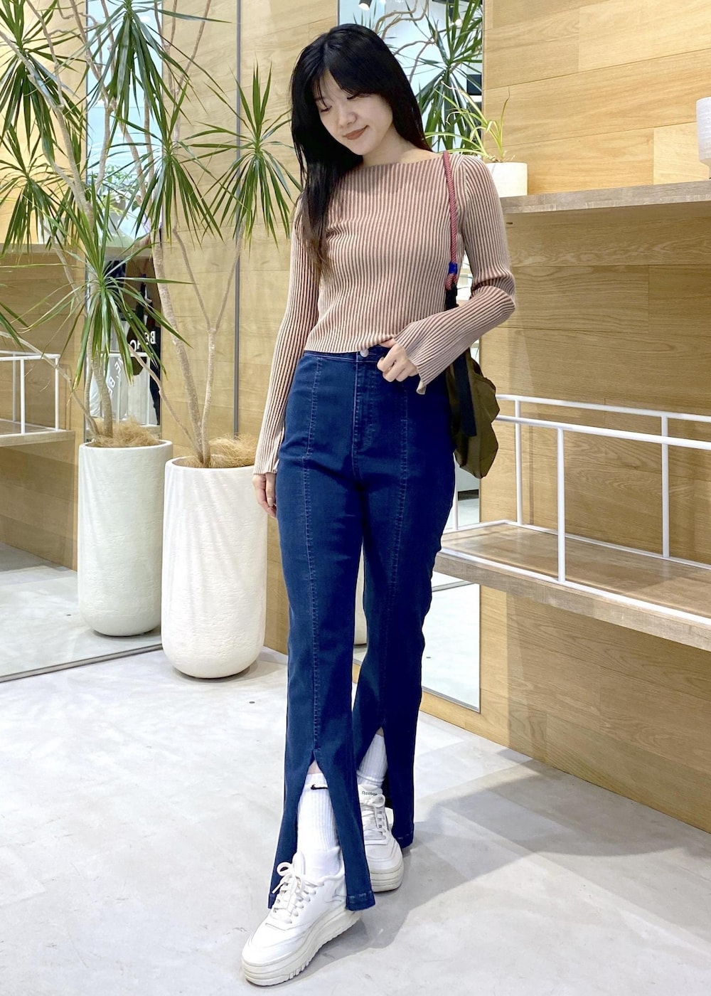 ホワイト系のスニーカー、ブルー系のデニムパンツ、グリーン系のショルダーバッグを着用したレディースの秋コーディネートの8枚目の写真