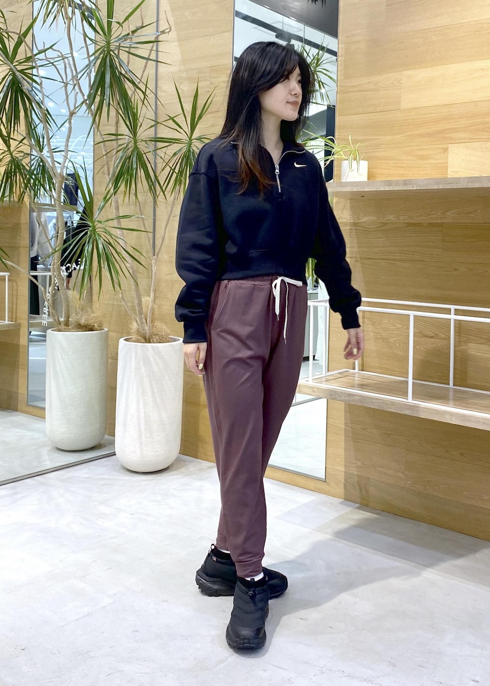 ピンク系のスラックス、ブラック系のスニーカー、ブラック系のスウェットを着用したレディースの秋コーディネートの2枚目の写真