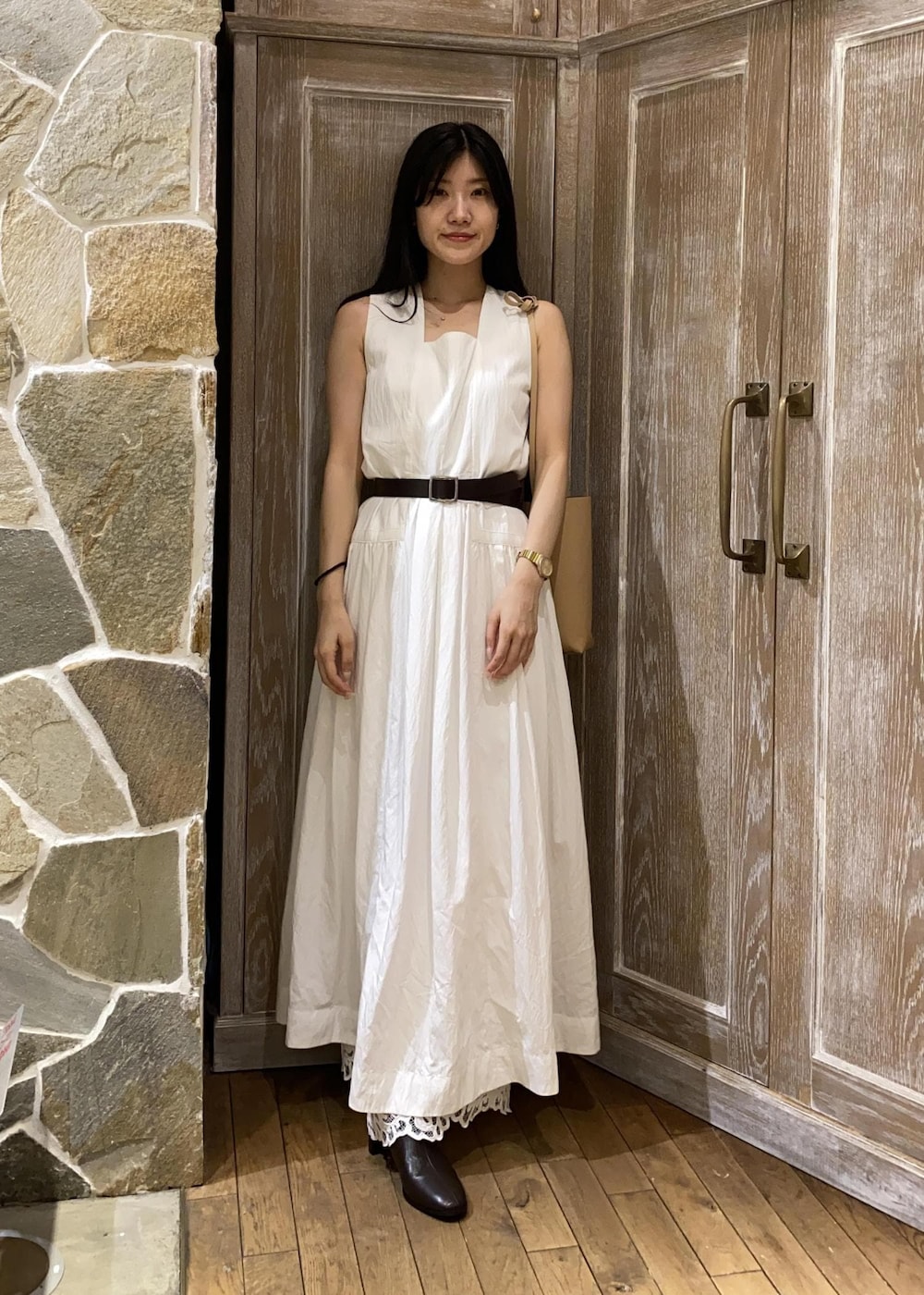 ベージュ系のショルダーバッグ、ホワイト系のワンピース、ブラウン系のサンダルを着用したレディースの夏コーディネートの2枚目の写真