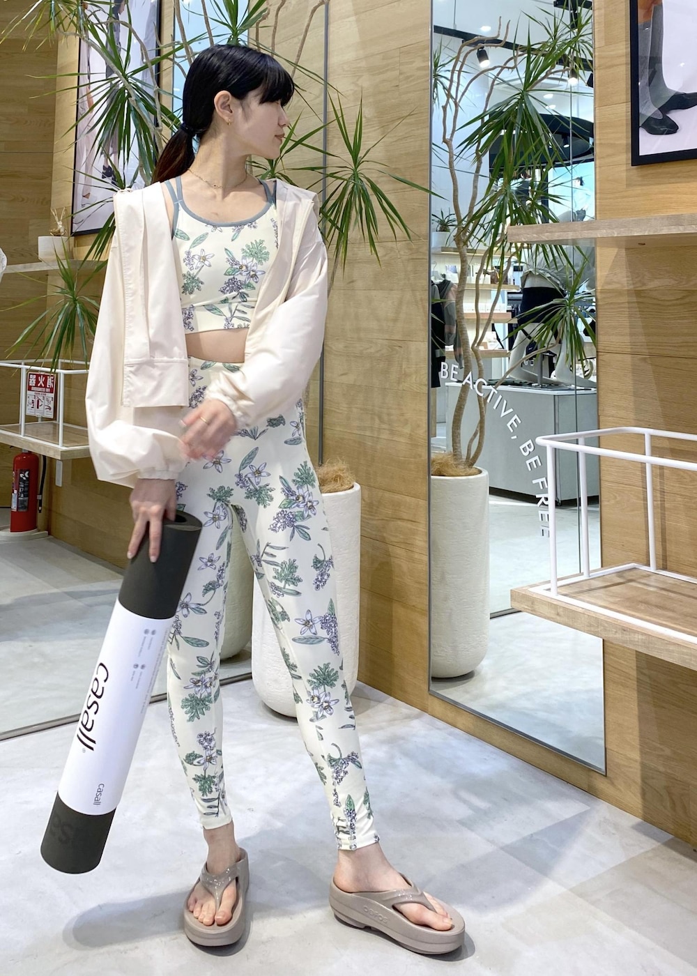 ベージュ系のサンダル、ホワイト系のラッシュガード、グリーン系のスポーツグッズを着用したレディースの夏コーディネートの3枚目の写真