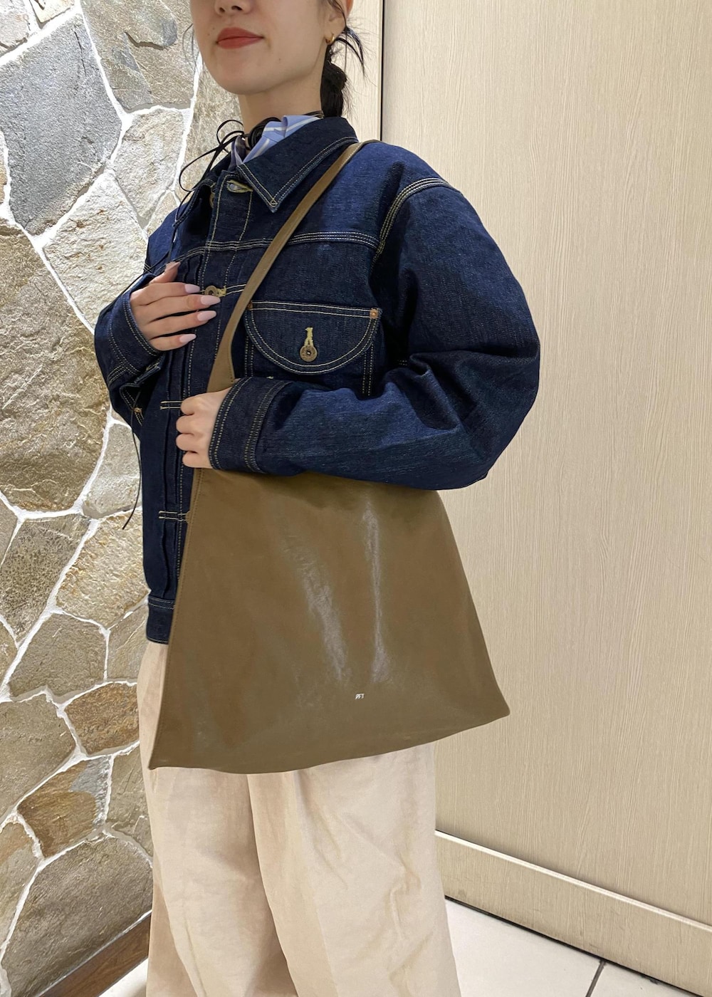 グリーン系のショルダーバッグ、ブルー系のデニムジャケット、ホワイト系のその他パンツを着用したレディースの冬コーディネートの5枚目の写真