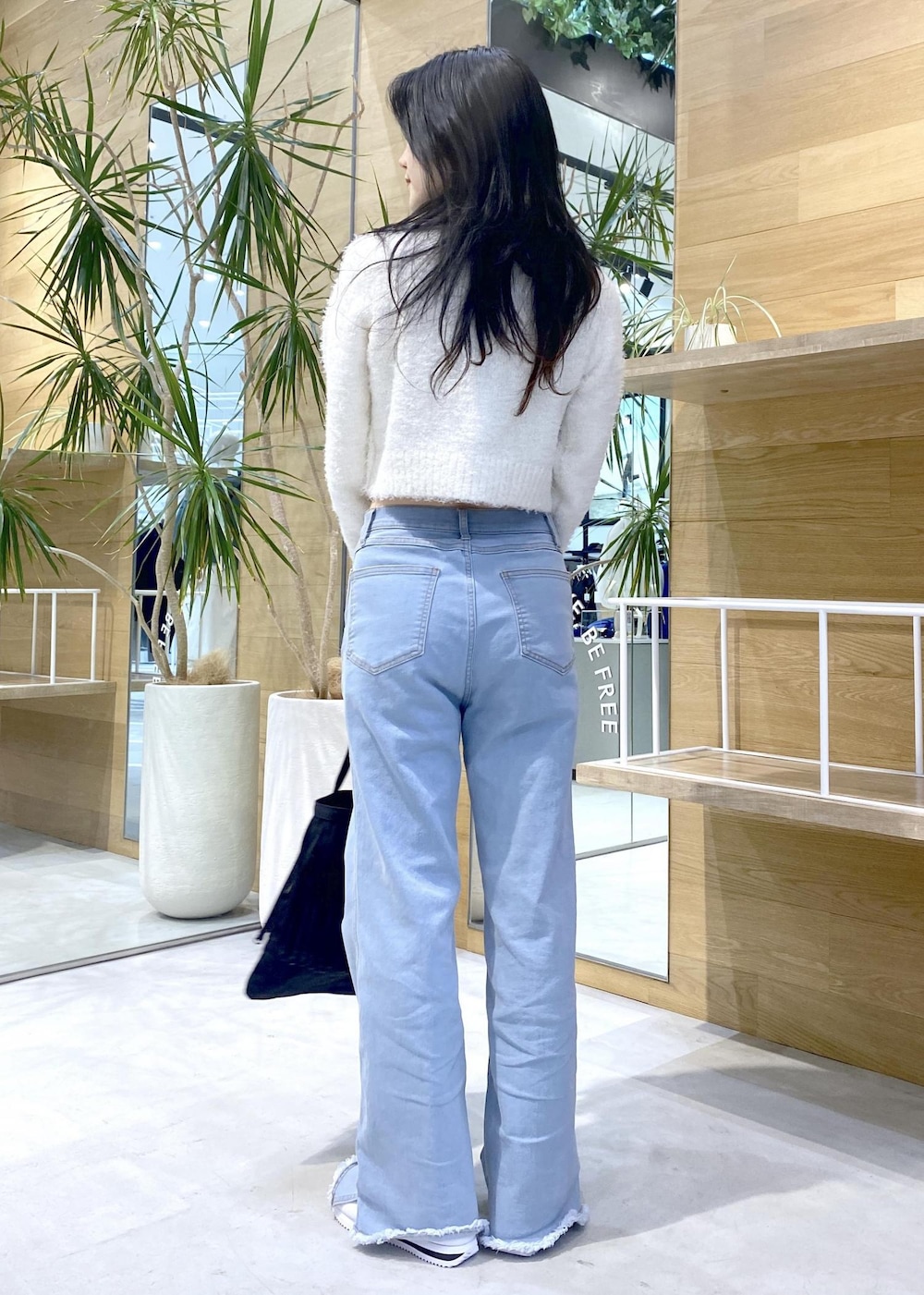 ホワイト系のスニーカー、ブルー系のデニムパンツ、ブラック系のトートバッグを着用したレディースの秋コーディネートの4枚目の写真