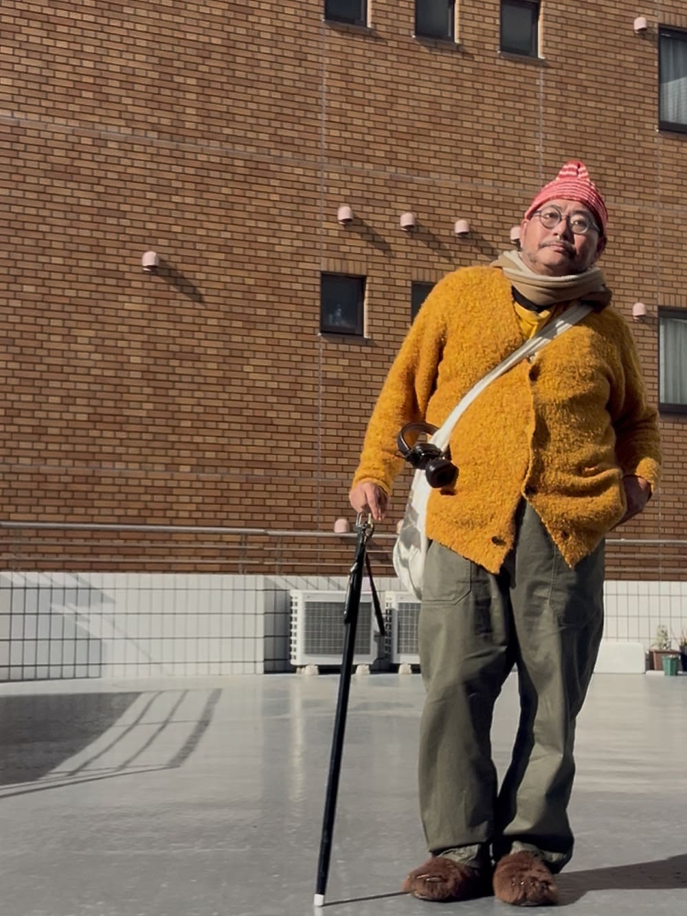 ブラウン系のサンダル、その他のニットキャップ/ビーニー、ブラウン系のマフラーを着用したメンズの冬コーディネートの2枚目の写真