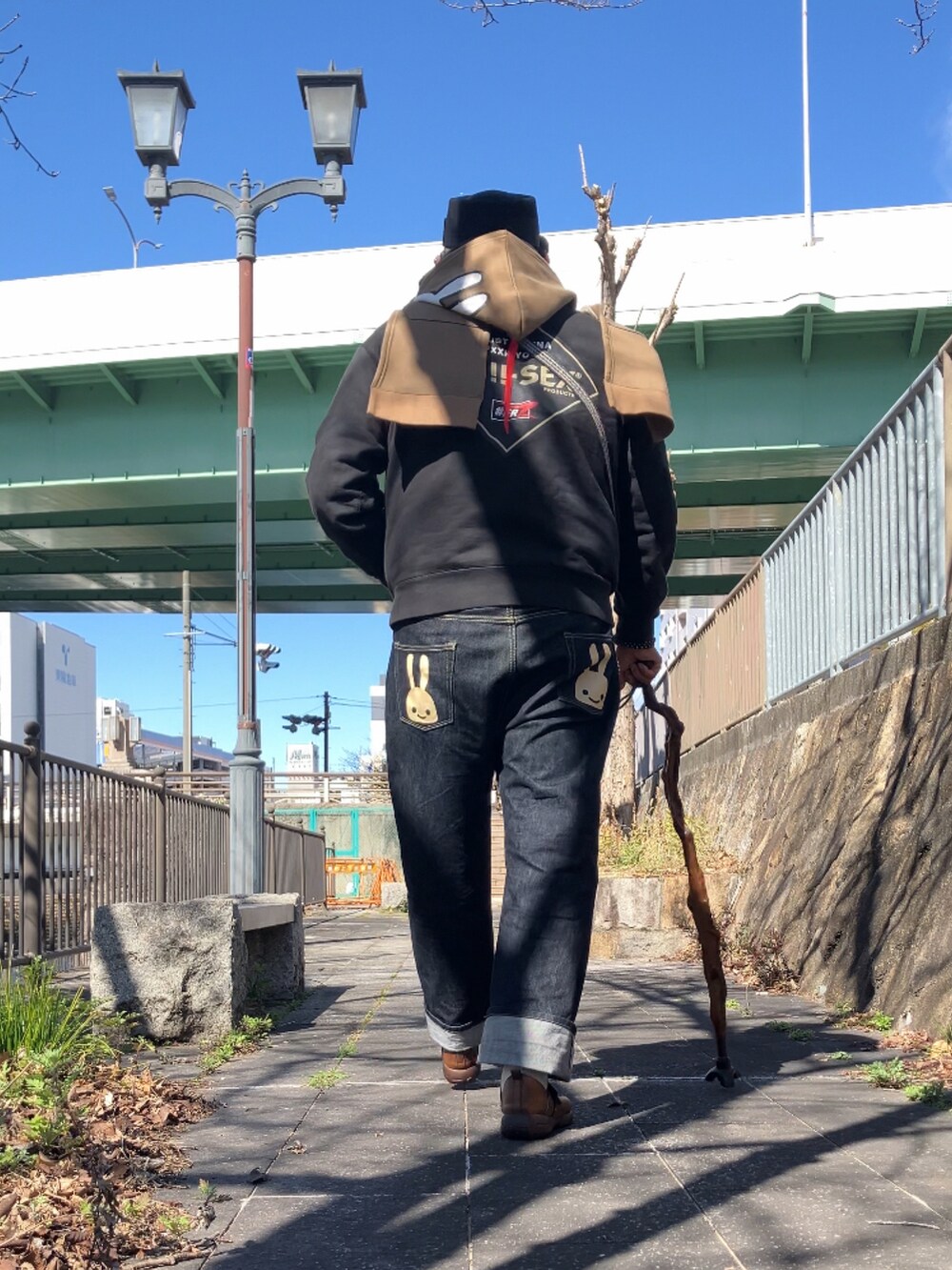 ブラック系のパーカー、ブラウン系のスリッポン、ブルー系のデニムパンツを着用したメンズの冬コーディネートの4枚目の写真