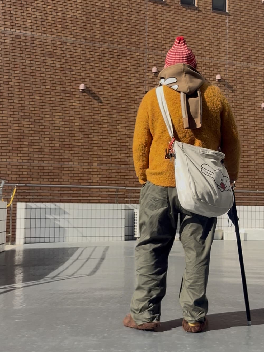 ブラウン系のサンダル、その他のニットキャップ/ビーニー、ブラウン系のマフラーを着用したメンズの冬コーディネートの3枚目の写真