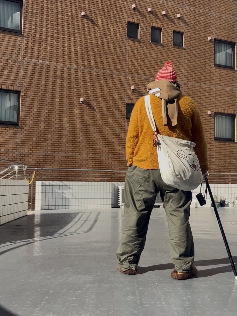 ブラウン系のサンダル、その他のニットキャップ/ビーニー、ブラウン系のマフラーを着用したメンズの冬コーディネートの4枚目の写真