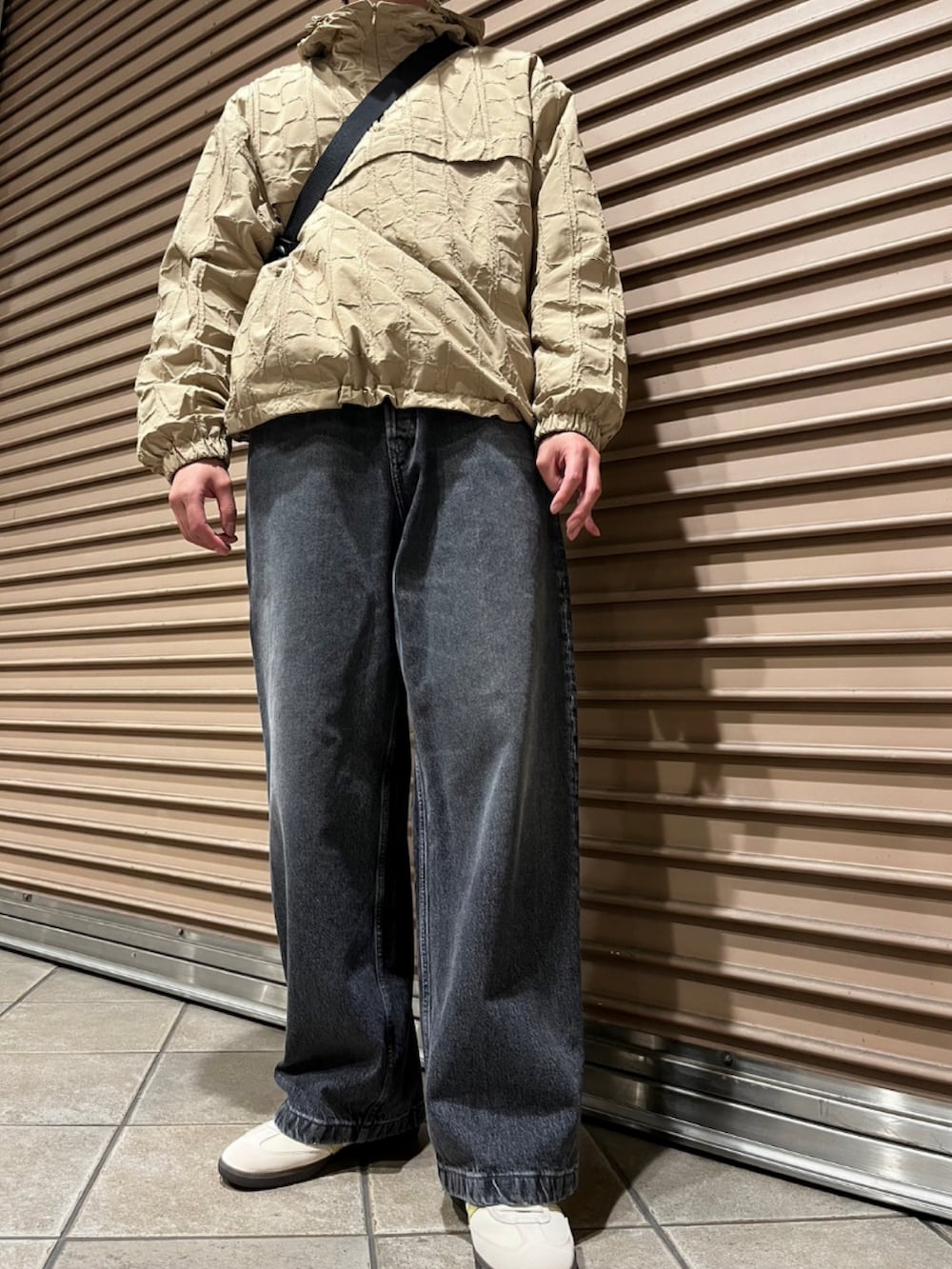 ベージュ系のブルゾン、ブラック系のショルダーバッグ、ブラック系のデニムパンツを着用したメンズの秋コーディネートの3枚目の写真