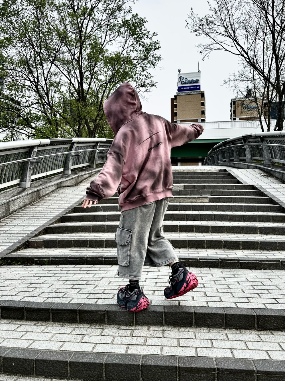 ピンク系のパーカー、グレー系のその他パンツ、グレー系のスニーカーを着用したメンズの夏コーディネートの3枚目の写真