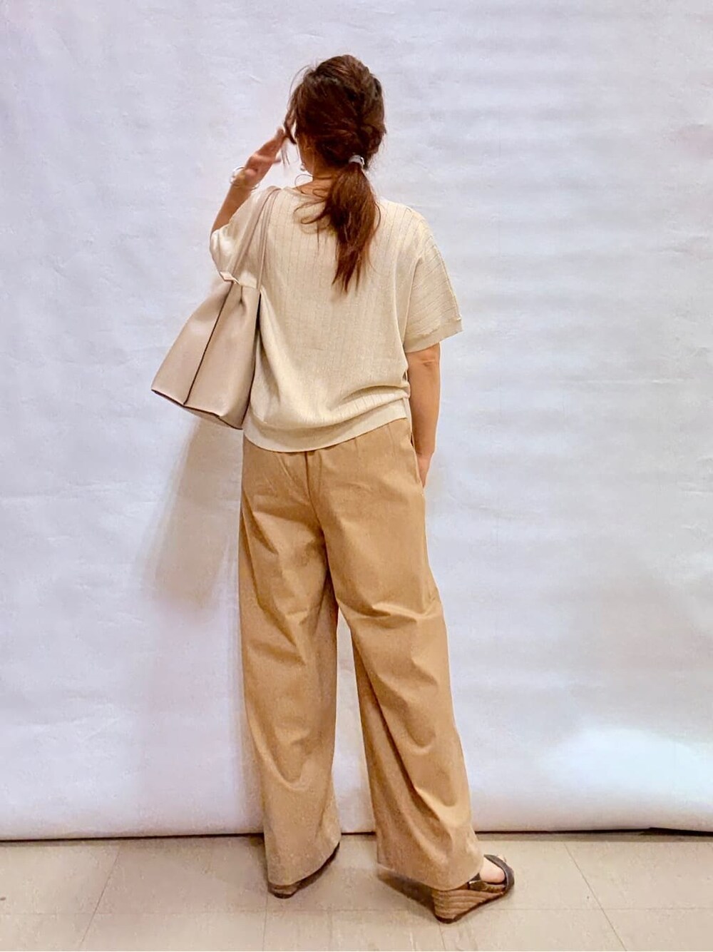 ゴールド系のニット/セーター、ベージュ系のその他パンツ、その他のサンダルを着用したレディースの夏コーディネートの3枚目の写真