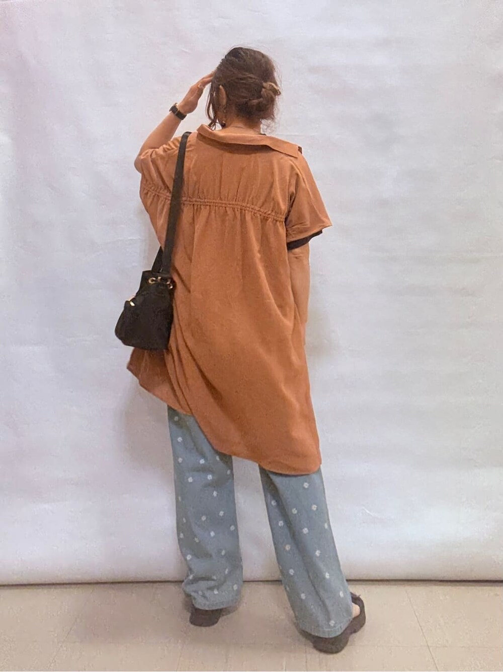 オレンジ系のチュニック、グレー系のTシャツ/カットソー、ブルー系のデニムパンツを着用したレディースの秋コーディネートの3枚目の写真