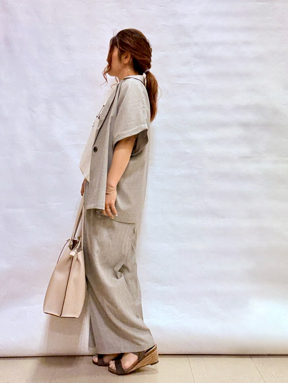 グレー系のテーラードジャケット、グレー系のトートバッグ、その他のサンダルを着用したレディースの夏コーディネートの2枚目の写真