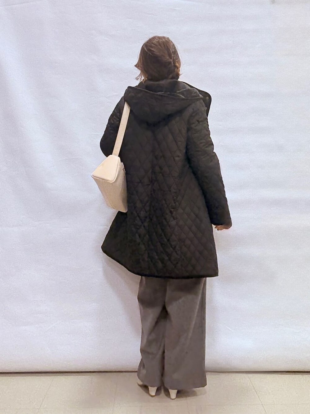 ブラック系のその他アウター、ホワイト系のニット/セーター、グレー系のその他パンツを着用したレディースの冬コーディネートの3枚目の写真