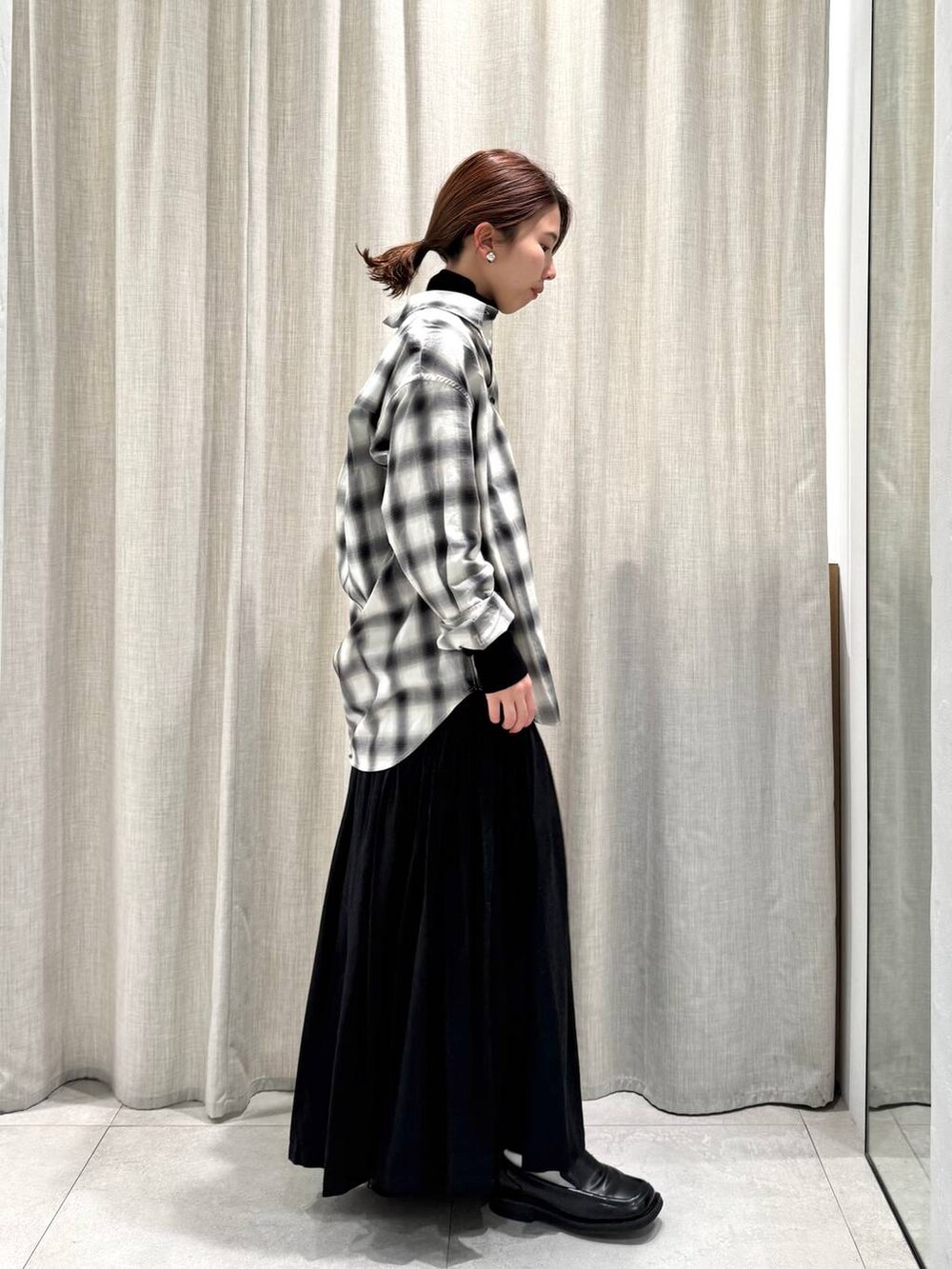 ブラック系のニット/セーター、ブラック系のシャツ/ブラウス、ブラック系のスカートを着用したレディースの冬コーディネートの6枚目の写真