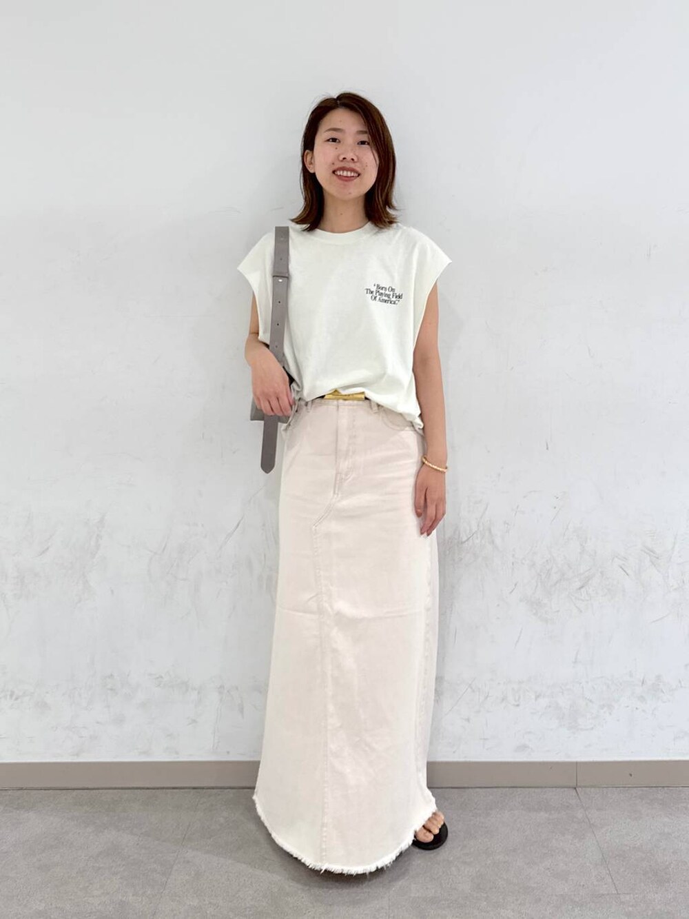 ブラウン系のサンダル、ホワイト系のTシャツ/カットソー、グリーン系のショルダーバッグを着用したレディースの夏コーディネートの3枚目の写真