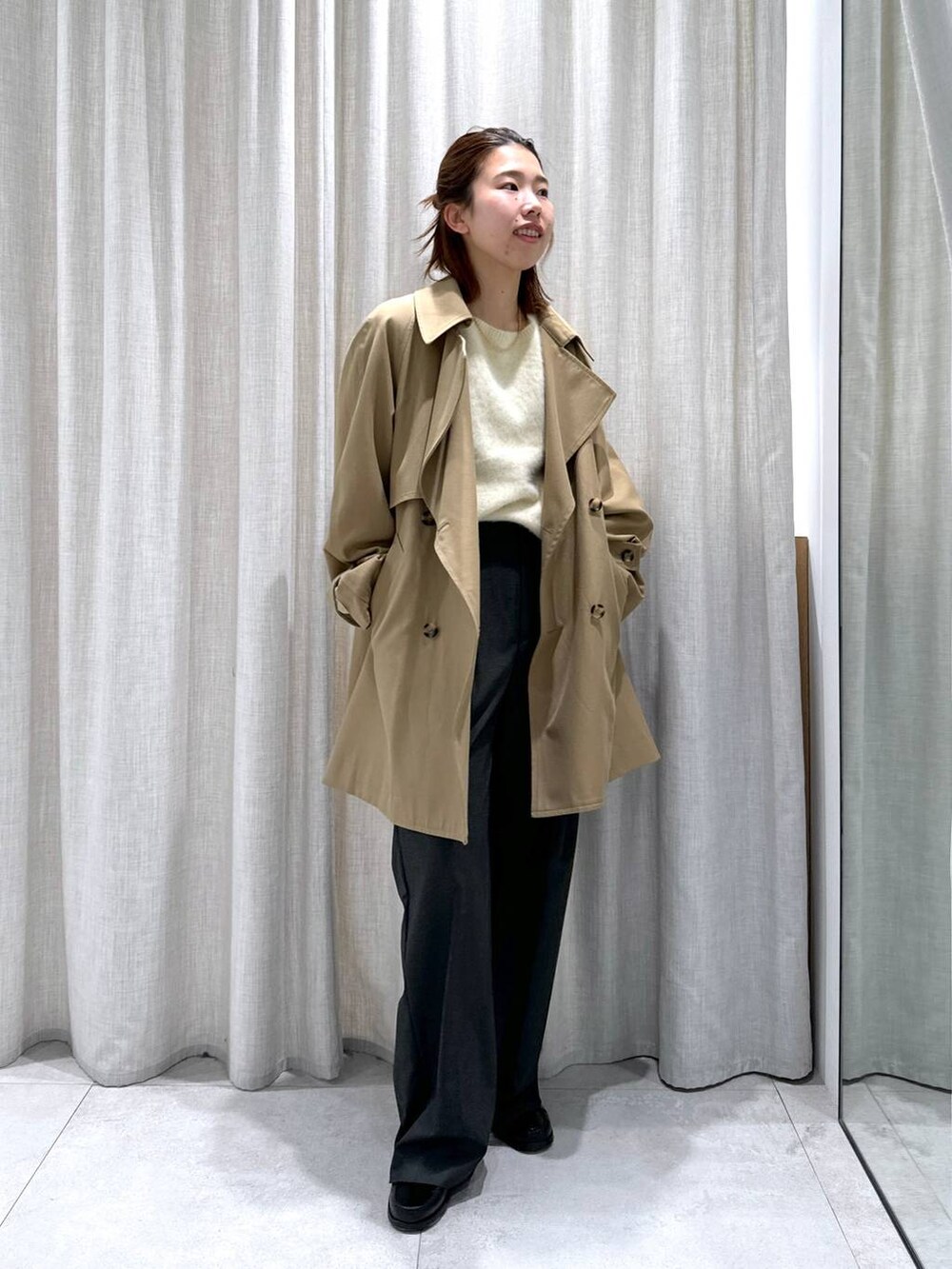 グレー系のスラックス、イエロー系のトレンチコート、イエロー系のニット/セーターを着用したレディースの秋コーディネートの3枚目の写真