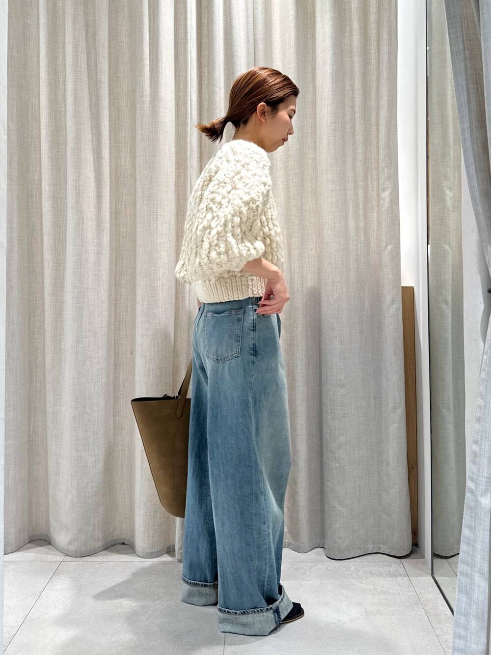 ベージュ系のカーディガン/ボレロ、ブラウン系のサンダル、ブルー系のデニムパンツを着用したレディースの秋コーディネートの5枚目の写真