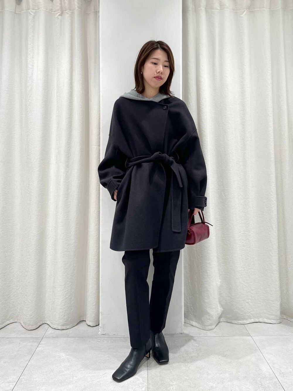 レッド系のショルダーバッグ、ブラック系のスラックス、グレー系のパーカーを着用したレディースの秋コーディネートの8枚目の写真