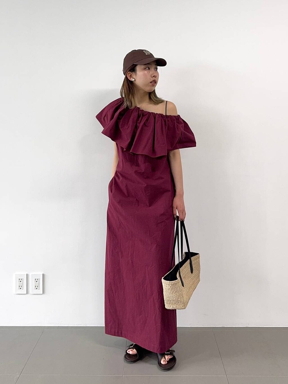 ベージュ系のかごバッグ、レッド系のワンピース、ブラウン系のキャップを着用したレディースの春コーディネートの5枚目の写真