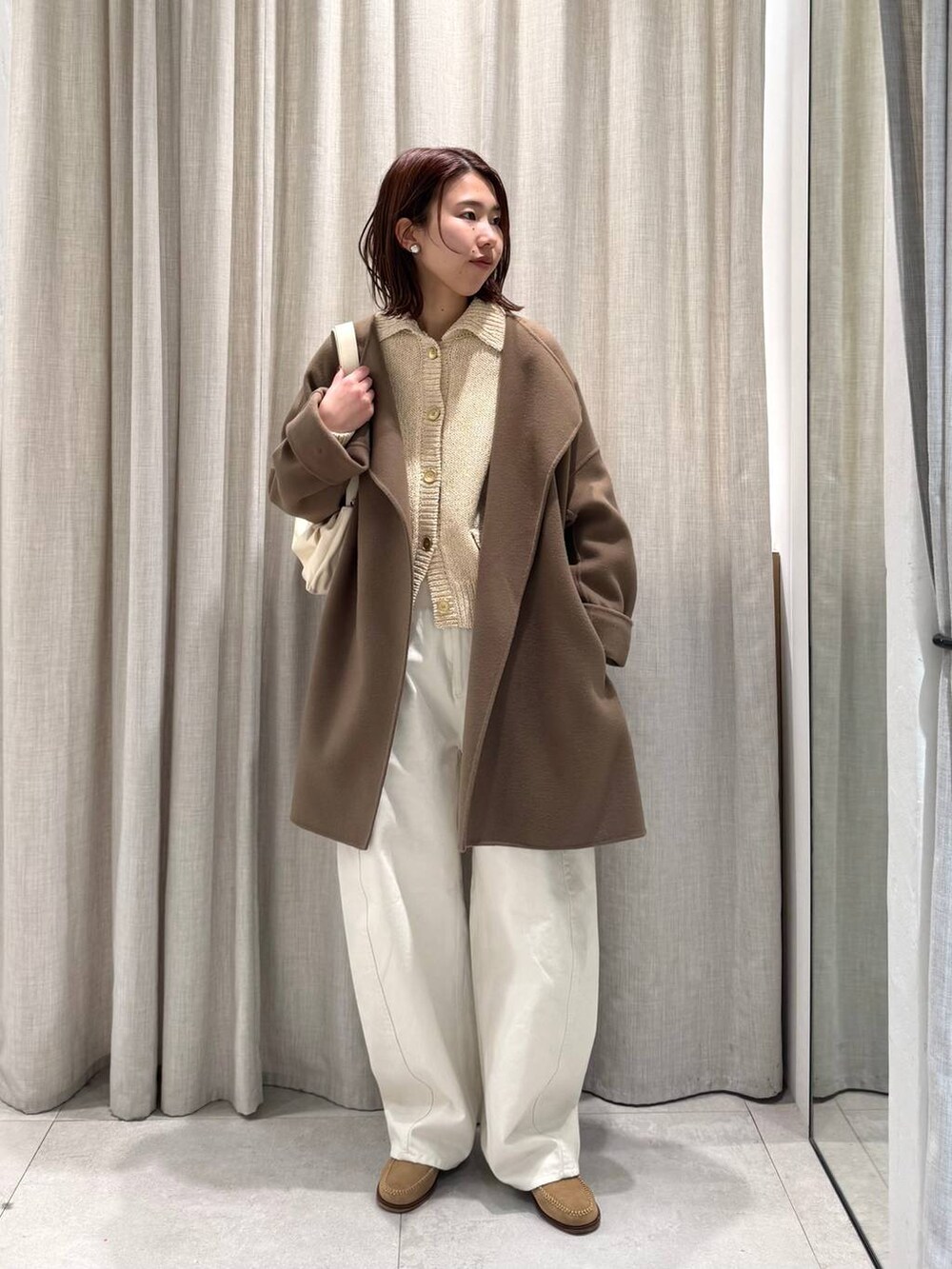 ベージュ系のショルダーバッグ、グリーン系のピーコート、ホワイト系のその他パンツを着用したレディースの冬コーディネートの3枚目の写真