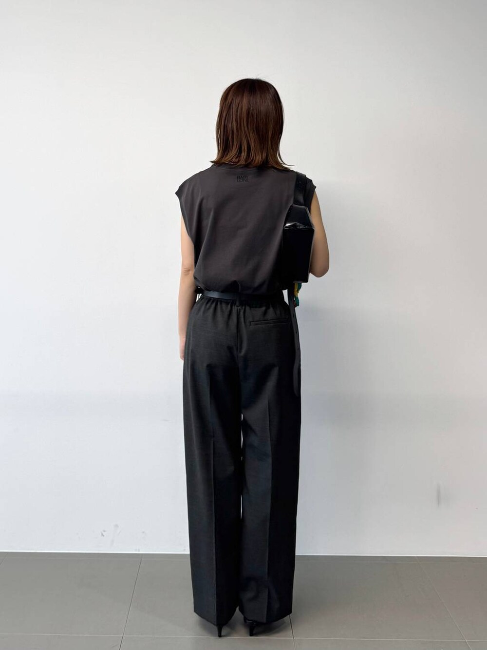 グレー系のタンクトップ、グレー系のスラックス、ブラック系のショルダーバッグを着用したレディースの夏コーディネートの5枚目の写真