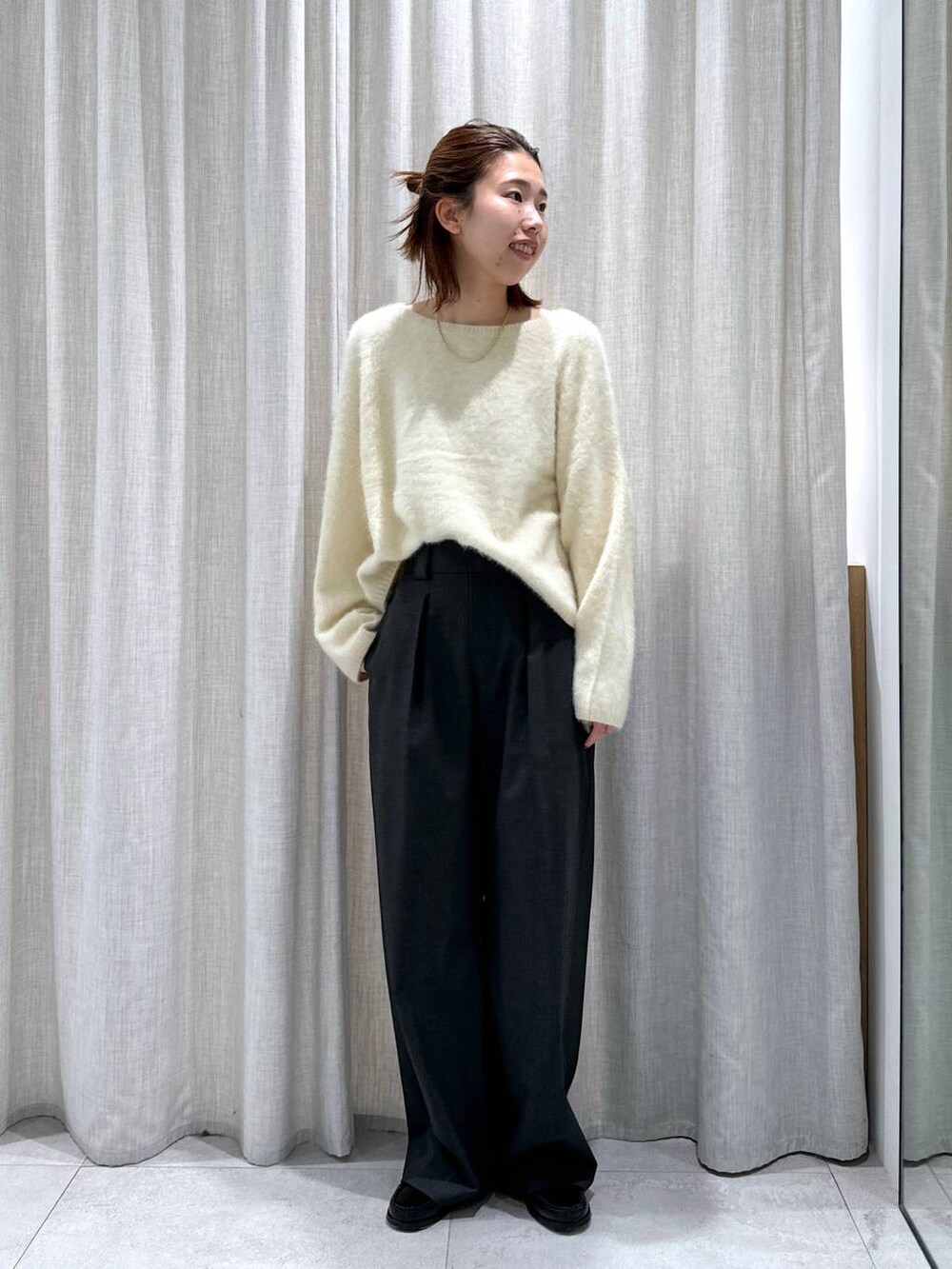 グレー系のスラックス、イエロー系のニット/セーターを着用したレディースの秋コーディネートの2枚目の写真