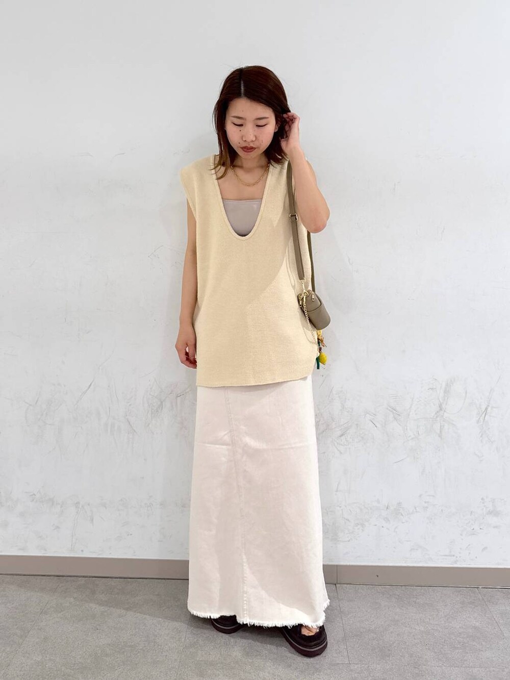 オレンジ系のキャミソール、ホワイト系のスカート、ベージュ系のベストを着用したレディースの夏コーディネートの3枚目の写真